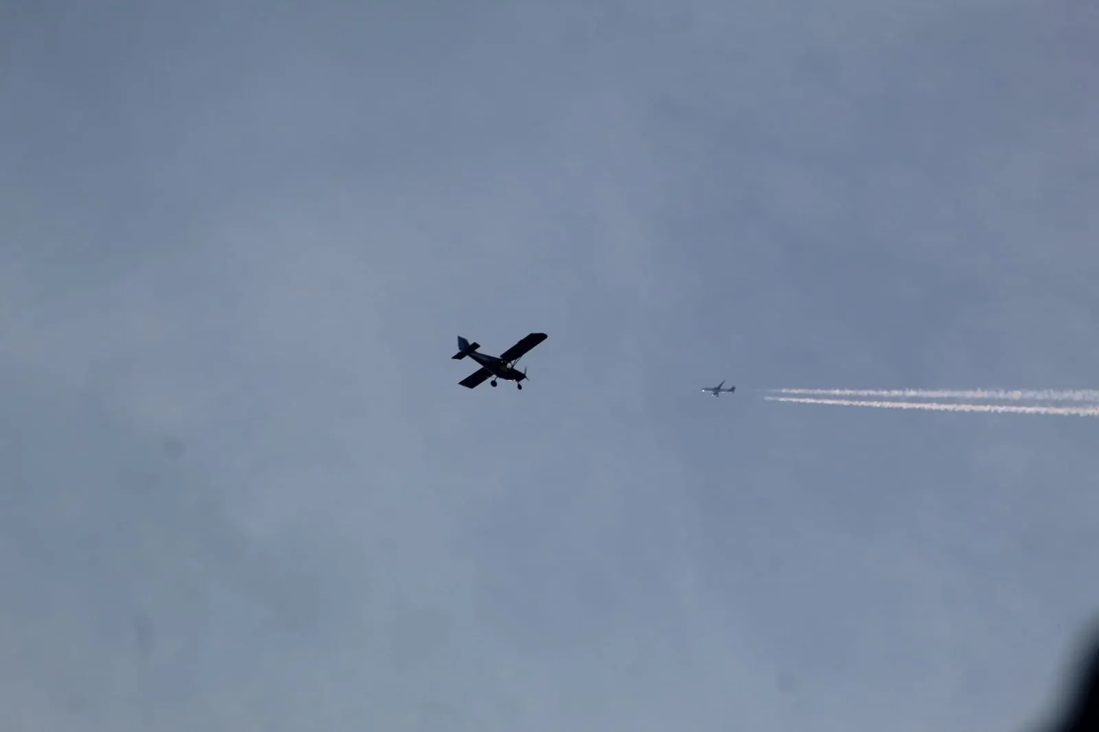 Un ULM en vol, avec un avion de ligne au loin